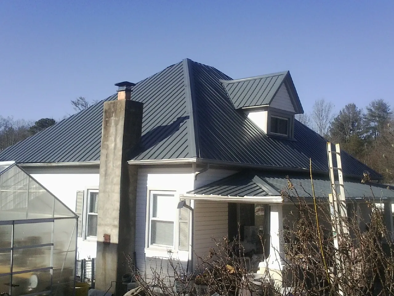 Dark blue standing seam metal roof on a white farmhouse with dormer — Slate & Tile Roof Repair by Roofing Brothers in Gore
