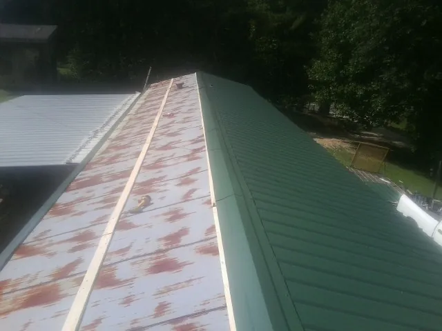 Old rusted panels beside newly installed green metal roofing — Wind Damage Roof Repair by Roofing Brothers in Gore