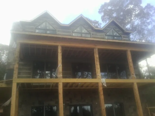 Dormers and porch framing on a large log home under construction — Roof Coating work by our crew in Gore