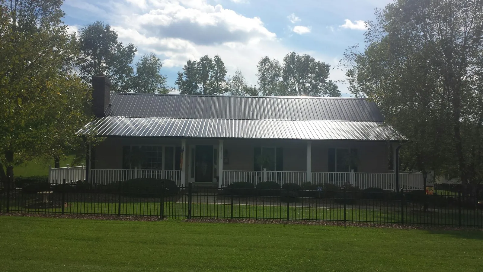 Gray metal roof on a brick ranch with a full width front porch — Gutter Guard Installation work by our crew in Gore