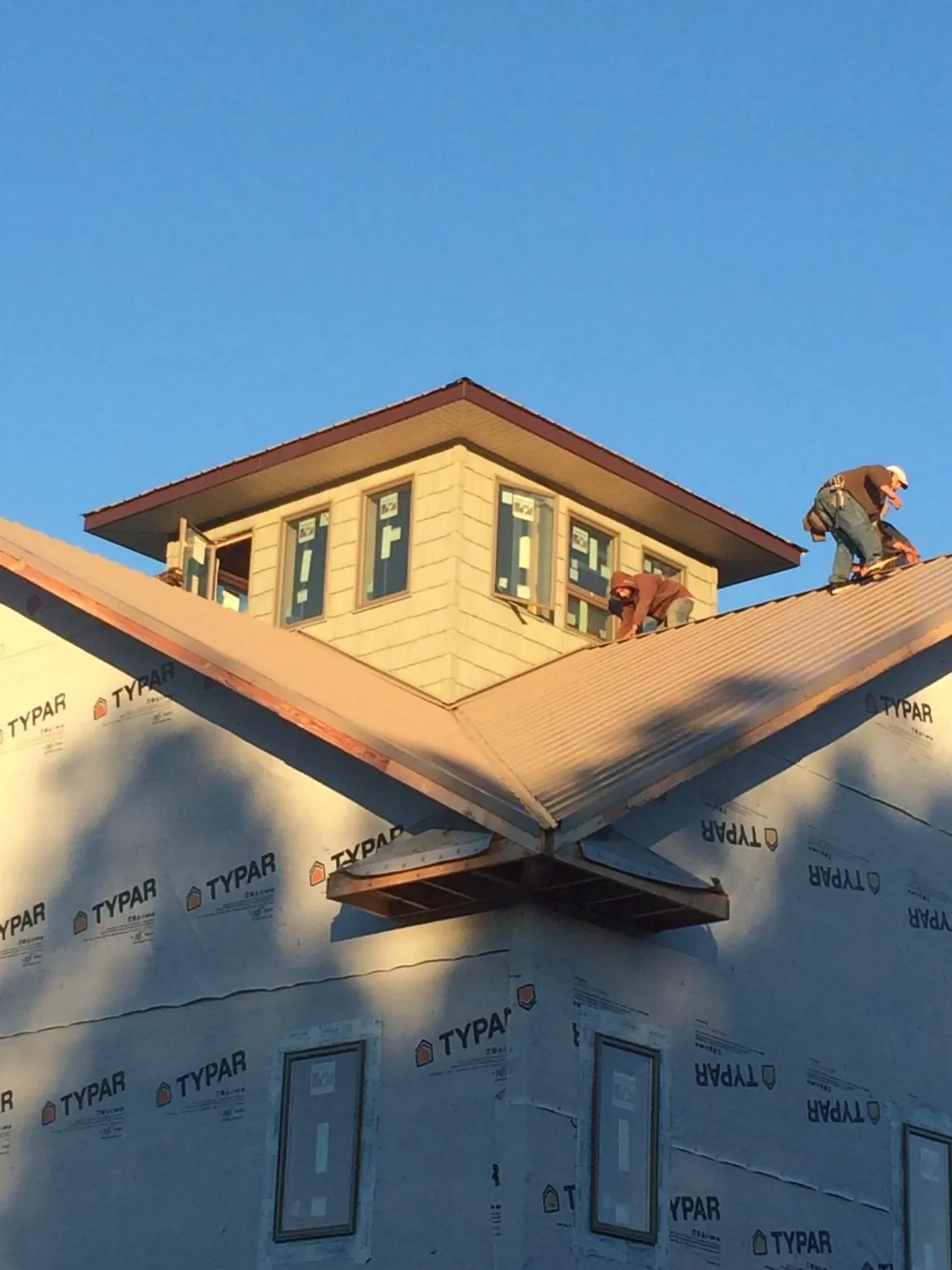 Roofers working around a rooftop cupola on a new metal roof at sunset — Roof Waterproofing in Gore by Roofing Brothers